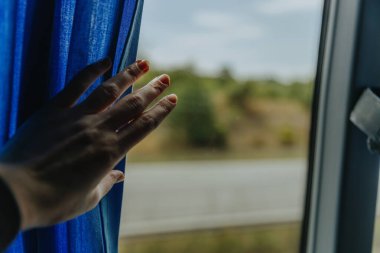 Bir beyaz kızın eli, yaz aylarında kasvetli ve yağmurlu bir günde otobüs camındaki perdeyi geri çeker. Doğa hareketi bulanıktır. Yandan görüntü ve metin için fotokopi alanı vardır.