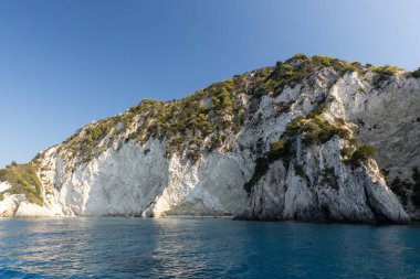 Güneşli bir yaz gününde ıssız bir sahili olan, mavi denizde yeşil kayalık bir adanın güzel panoramik manzarası..