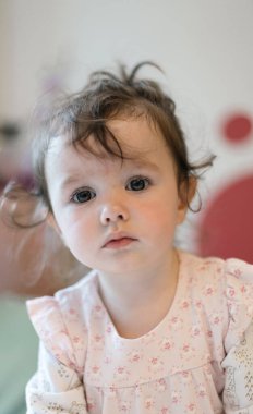 Kafasında at kuyruğu olan, güzel, beyaz bir kızın portresi. Elbisesinin kenarına bakıyor..