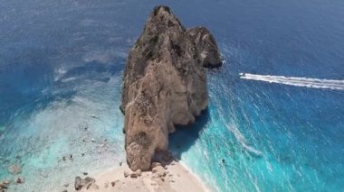 Güzel panoramik bir dağ manzarası... Mavi İyon Denizi 'nde kayalık sahil kenarında keskin bir tepesi olan... kuş bakışı ve güneşli bir yaz günü... arasında seyreden bir motorlu tekne.