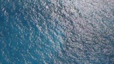 Güneşli bir yaz gününde, şeffaf, temiz, masmavi bir suyun güzel atmosferik manzarası, yukarıdan yakın çekim, elde taşınabilir çekim. Seyahat zamanı konsepti, doğal arka planlar.