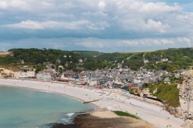 Kuzey Denizi 'nin etretat, Normandiya' daki yeşilliklerle çevrili güzel bir köy. Açık bir bahar gününde turistler yukarıdan yakın çekim yaparak dinleniyor..