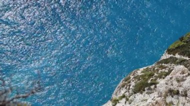 Güneşli bir yaz gününde, temiz, berrak, masmavi bir suyun güzel atmosferik manzarası, tepeden yakın çekim, el kameralı çekim, yavaş çekim. Seyahat zamanı konsepti, doğal