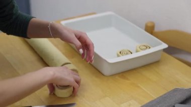 Tanınmayan genç bir Kafkas kızı, kesilen hamur parçalarını şeker ve tarçınla birlikte ahşap bir masada beyaz bir kabın içine koyar. Cinnabon tarifi kavramı adım adım