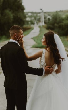 Genç, güzel, şık, beyaz bir çift gelin ve damadın portresi. Birbirlerine sarılıyorlar. Bulanık bir yolun arka planına aşkla bakıyorlar.