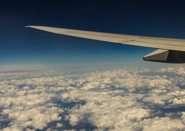 Gökyüzüne karşı beyaz bulutlar oluşturan bir uçak kanadının güzel bir görüntüsü pencerenin içinden sağa doğru dönüyor..