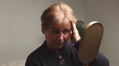 Beyaz, yaşlı, güzel bir kadın elinde tuttuğu aynaya bakar ve saçlarının ve kaşlarının tamamlanmış rengine hayran kalır. Akşamları bir güzellik salonunda oturur.