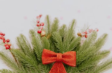 Bir buket köknar dallı kırmızı bir fiyonk soluk mavi bir arkaplanda uzanır..