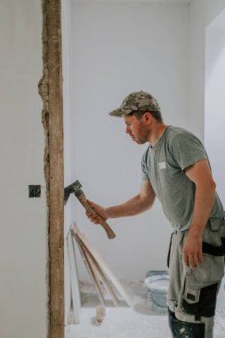 Kafkasyalı genç bir adam, tanınmaz halde, balta ile temizliyor. İskelenin dibindeki eski macunu, bir açıda dikilirken, seçici bir odak ile yakından bakıyor. İnşaat