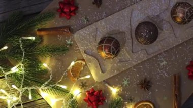 Üç güzel çikolatalı tatlı, Noel ağacı şeklinde. Kağıt peçeteli bir masanın üzerinde duruyor. Yanan bir çelenk, porselen bir ev ve şenlikli bir dekor.