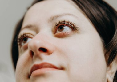 Kısa saçlı, kahverengi gözlü, güzel, beyaz tenli bir kızın portresi. Geniş kirpikleri kabarık. Ev ofisinin kozmetoloji masasında otururken yan tarafa bakıyor.