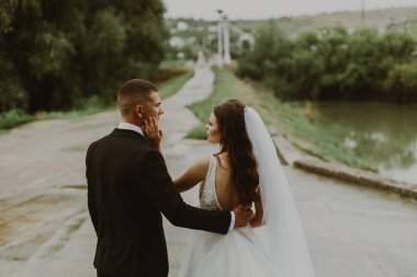 Gelin ve damadın genç, güzel, şık, beyaz bir çiftin portresi. Yarım tur sonra arka tarafta durup birbirlerine sarılıyorlar. Aşkla birbirlerine bakıyorlar.