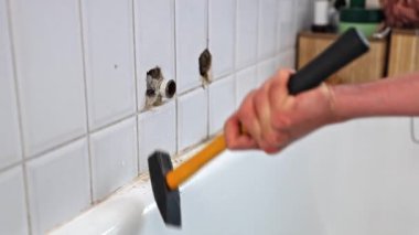 Kafkasyalı genç bir adamın elleri tanınmaz halde borunun üzerinde sarı bir çekiçle vuruyor musluktan çıkan bir çekiçle gün boyunca tuvalette dikilirken tamir ediyor, kapatıyordu.