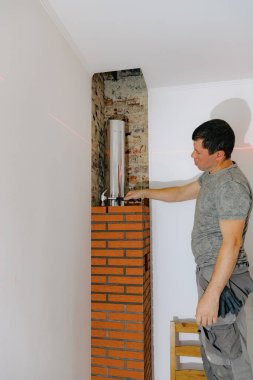 Genç yakışıklı beyaz bir adam, şöminenin bacasına çekiçle tuğla vurur. Gün boyunca bir sandalyede dikilirken, sıcaklığı ve sıkılığı kontrol eder.