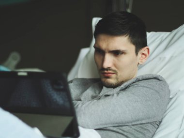 Kafkasyalı bir gencin portresi yatakta yatıyordu ve dikkatlice hastane odasındaki tablete bakıyordu..