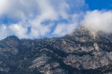 İtalya 'nın Positano kentinde güneşli bir yaz gününde, bulutlu bir gökyüzü karşısında yeşil bitki örtüsü olan kayalık tepelerin güzel manzarası. Güzel arka plan ve duvar kağıtlarını kavra.