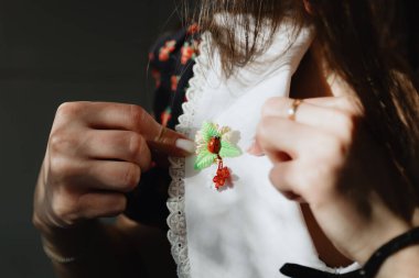 Çok güzel bir kızın portresi, güneşli bir günde küçük bir ev yapımı martisor ile uğurböceği ve çiçekleri klasik koyu renkli bir elbisenin beyaz yakasına dikmişti. Konsept