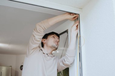 Kafkasyalı, mutlu, esmer, genç bir adamın portresi. Kapı çerçevelerinin üst köşesinde, yakın çekimde otururken yalıtkan, kauçuk, kendine yapıştırıcı bir profil çiziyor. Şey...