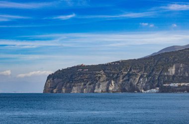 Kayalık bir adanın açık güneşli bir havada, açık denizde binaları ve bitkileri olan, İtalya 'nın Capri şehrinde bulutlu bir gökyüzü olan güzel bir manzarası var. Güzel doğa kavramı