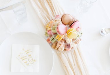 Bahar pastel gölgelerindeki çok renkli mini badem kurabiyelerinin çok katmanlı şeffaf bir tabakta, peçeteli tabaklar arasında, üst katlı çok yakın plan bir masa üzerinde durması çok güzel. Kavram