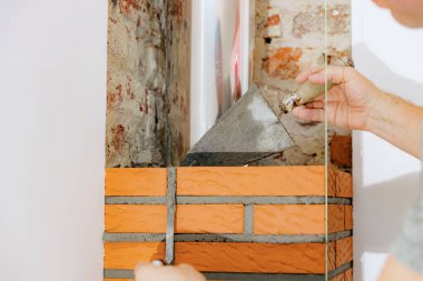 Genç bir Kafkasyalı, şöminenin bacasındaki tuğlaya taze çimento harcı ile bir spatula sürüyor. Gün boyunca bir sandalyenin üzerinde duruyor.