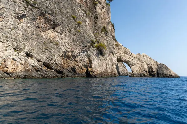 Güneşli bir yaz gününde, açık gökyüzü, zakynthos adasında, mavi denizde küçük kayalık bir kemerin güzel manzarası..