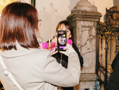 Kafkasyalı genç bir kızın portresi arkada duruyor ve elinde waffle ile akıllı bir telefonla fotoğraf çekiyor, bir bahar gecesi şehirde yürüyor, yan görüş, yakın çekim. Kavram
