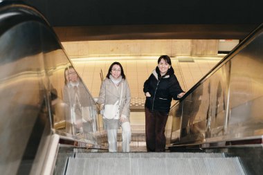 İki güzel beyaz kız turistin portresi. Birlikte kameraya bakıyorlar ve bir bahar gecesi metrodan tek başlarına çıkmak için yürüyen merdivene çıkıyorlar. Kavram