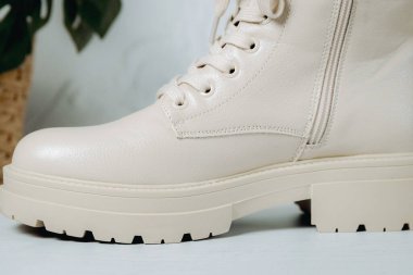 Bir parça şık şık kadın klasik krem rengi botlar sert tabanlı, bağcıklı ve tokalı, beton zeminde duruyor, alt tarafı çok yakın. Kadın ayakkabıları, moda kavramı