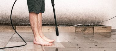 Tanımlanamayan, çıplak ayaklı, beyaz bir adam, bir bahar günü evinin arka bahçesinde bir kercher kullanarak, basınçla kirli bahçe fayanslarını yıkıyor.