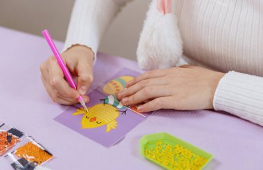 Tanımlanamayan beyaz bir kızın portresi leylak masasında oturuyor ve kendi elleriyle kart hazırlıyor, bahar günü evde bir Paskalya fıstığına sahte elmaslar yapıştırıyor, seçici bir odak ile çok yakından bakıyor. Yaratıcılık kavramı