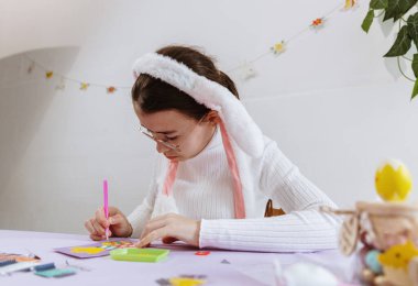 Leylak masasında oturup kendi elleriyle paskalya yumurtalarına sahte elmaslar yapıştıran ve bahar günü mutfakta orta boy bir civciv yapan beyaz saçlı güzel bir kızın göğsüne portre.