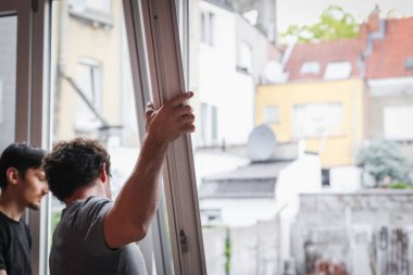 İki güzel Kafkasyalı esmer kadın, menteşeleri camlı bir pencere çerçevesi kuruyor. Tadilatın devam ettiği bir odada, yan taraflarda duruyorlar..