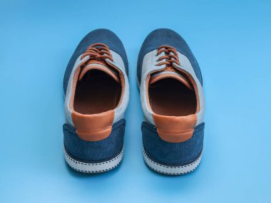 Bir çift kot spor ayakkabısı mavi arka planda, yakın planda duruyor. Moda konsepti, güzellik, erkek ayakkabıları.