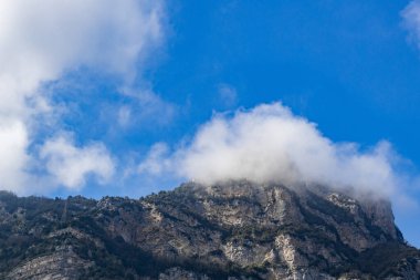 İtalya 'nın Positano kentinde güneşli bir yaz gününde, tepesinde beyaz bir bulut bulunan yeşil bitkilerle kayalık tepelerin güzel manzarası. Güzel arka plan ve duvar kağıtlarını kavra.