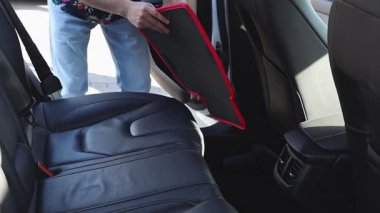 Yakışıklı beyaz bir adam, güneşli bir bahar günü şehir araba yıkama yerinde arka yolcu koltuklarının yanına koruyucu paspas seriyor. Üst tarafı yavaş çekimle çok yakından bakıyor. Konsept: araba yıkama zamanı, çalışan insanlar, teknoloji kullanımı.