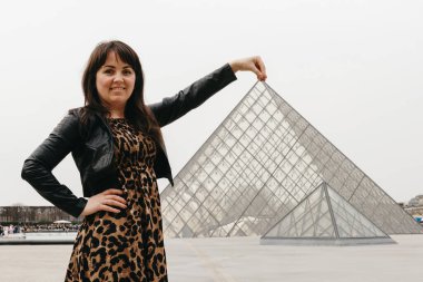 Hayvan desenli uzun elbiseli güzel beyaz bir kızın uzun bir portresi kaidede duruyor ve bahar günü elinde cam piramitle poz veriyor. Zaman yolculuğu kavramı, dinlenme zamanı arkadaşlar, mutlu.