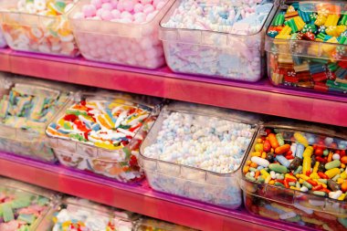 Renkli karışık jöle şekerlemelerinin çok güzel bir manzarası var. Pembe bir tezgahın üzerindeki şeffaf bir plastik kutuda. Yan görünüş çok yakın..