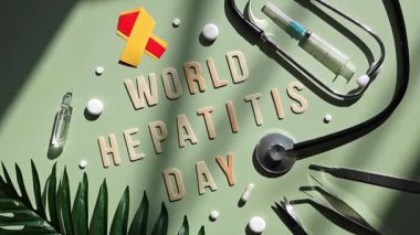 Stetoskop, kırmızı ve sarı kurdele, cerrahi aletler, haplar, şırınga ve hafif ahşap harflerle hizalanmış Dünya Hepatit Günü, atmosferik soyut gölgeler ile yeşil bir zemin üzerinde uzanır, sağ ile düz yakın yatar