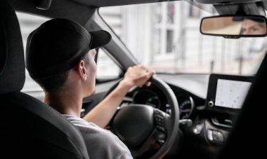 Bir yaz günü direksiyonun arkasında yan yan oturan, dikiz aynasından yansıyan, tarlanın derinliğine yakın bir şekilde bakan beyaz bir adamın güzel bir manzarası..