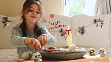 Kafkasyalı güzel bir esmer kız Cadılar Bayramı şekerlerini alır ve onlarla oynar, onları gözlerinin önünde tutar, başını sallar ve tebrik eder, güneşli bir sonbahar sabahında yatak odasında oturur,