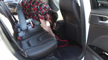 Güneşli bir bahar günü, şehir oto yıkama yerinde arka koltuklarda koruyucu paspas seren yakışıklı beyaz bir adam. Yavaş çekimde yan çekimde. Konsept: araba yıkama zamanı, çalışan insanlar, teknoloji kullanımı.