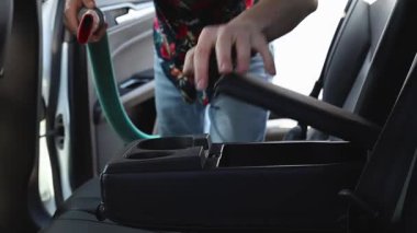 Yakışıklı beyaz bir adam güneşli bir bahar günü şehir araba yıkama yerinde iç mekanı süpürüyor. Yan görüntüsü yavaş çekimde. Konsept: araba yıkama zamanı, çalışan insanlar, teknoloji kullanımı.