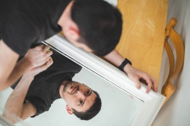 Koyu renk elbiseli beyaz tenli genç bir esmer, aseton kaplı sarı bir paçavrayla boya yaptıktan sonra aynayı yıkıyor, yansıyor, bir yaz günü mutfakta duruyor, üstten yakından bakıyor. Eski mobilyaları tamir etme fikri, yeni bir hayat..