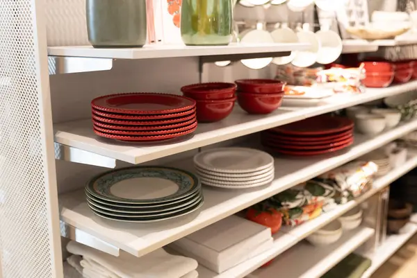 Alışveriş merkezindeki mağazanın tezgahında diğer mutfak eşyaları ve aksesuarlarla kırmızı şık tabakların güzel manzarası, seçici bir odak ile yan görüntü. Alışveriş zamanı konsepti.