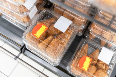 Mağazadaki tezgahın üzerinde duran şeffaf plastik kutuda taze pişmiş çok katmanlı kruvasanların güzel manzarası. Alışverişe çıkma zamanı hamur işleri, taze çörekler.