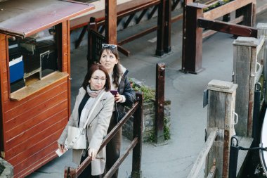 Güneşli bir bahar gününde şehrin terk edilmiş tekne turizm istasyonunda durup duygusal olarak etrafa bakınan iki güzel kızın portresi. Kavram, zaman aile yürüyüşü, zaman modern seyahat, zaman gemisi..