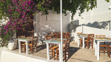 Güneşli bir yaz gününde, Yunanistan 'ın Rodos adasındaki Lindos' ta taş bir mozaik terası olan bir sokak kafesinin masa ve sandalyelerinin manzarası çok güzel. Seyahat zamanı konsepti, yaz zamanı, güzel arka planlar ve...