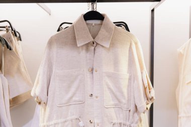 Güzel bir bej renkli keten ceket manzarası var. Alışveriş merkezindeki askıda asılı bel kemeri, yakın çekim. Konsept alışveriş zamanı, kadın kıyafetleri.