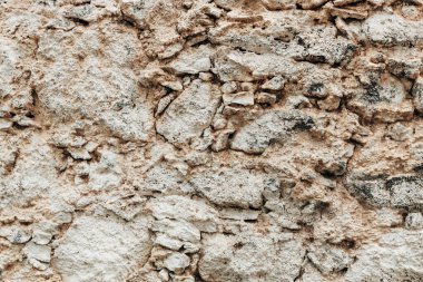 A beautiful horizontal view of a rocky texture made of irregularly shaped and sized stones in shades of gray and beige, mid-ground view. Concept: natural backgrounds and textures.